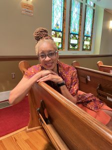 Woman sitting in church pew, stained glass windows