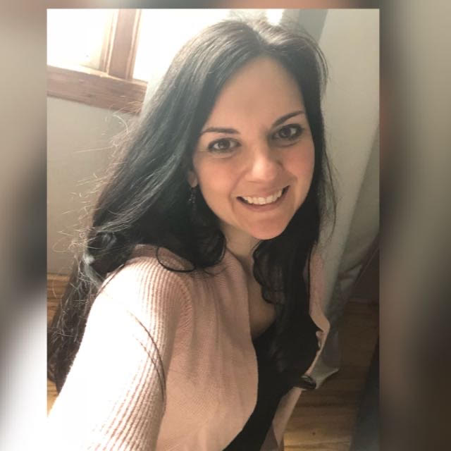 Woman smiling in a pink cardigan.