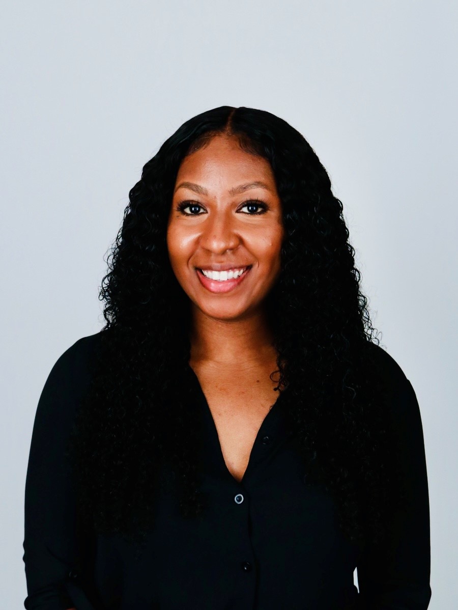 Smiling woman with curly hair in black shirt.