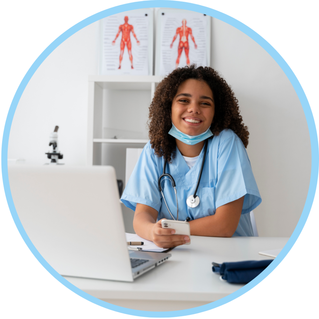 Smiling nurse in blue scrubs at a desk