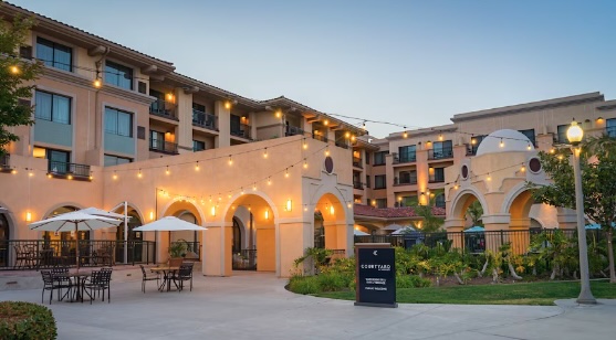 Courtyard hotel building with outdoor seating and lights.