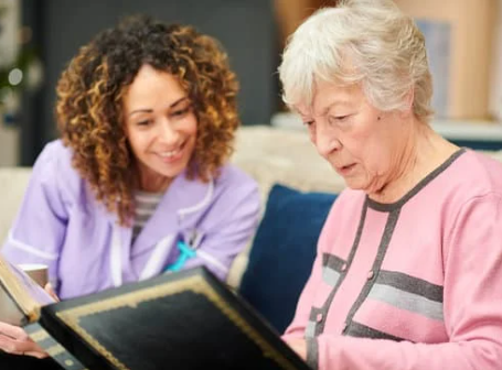 Caregiver and elderly woman looking at a photo album.