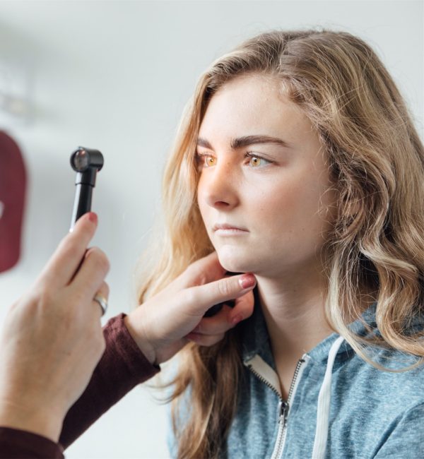 Eye exam with ophthalmoscope on young woman.